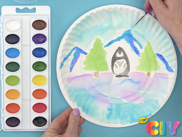 White paper plate with penguin and winter scene painted with Crayola Watercolors