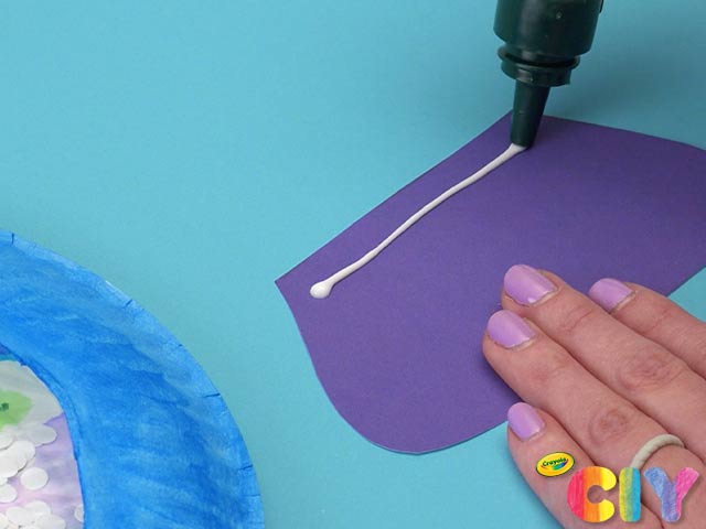 Liquid glue nozzle dispensing glue on cut-out purple snow globe base shape