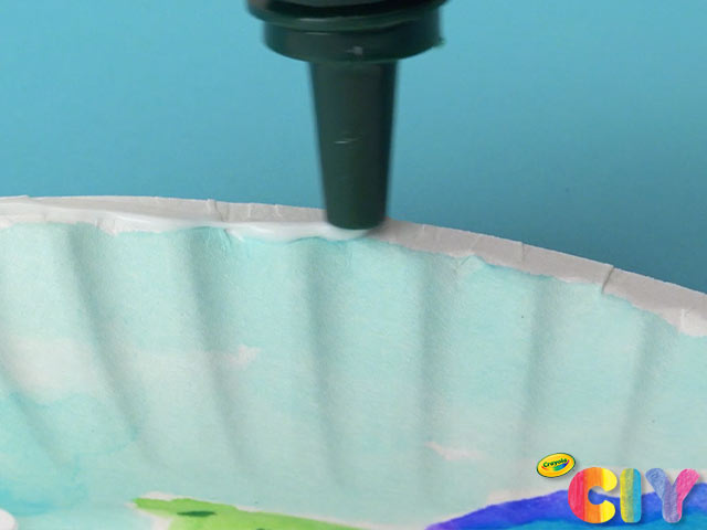 Liquid glue nozzle dispensing glue on paper plate edge