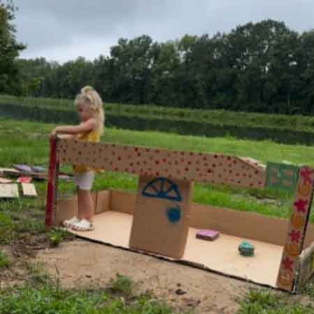 Child building cardboard fort. 