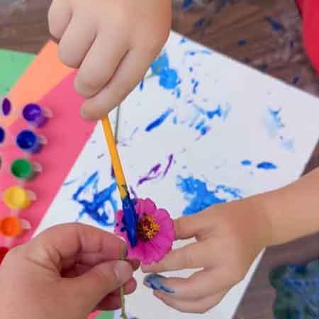 Child using flower as a paintbrush. 