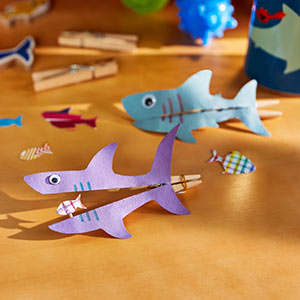 Paper shark silhouette eating fish glued to clothespin that opens and closes
