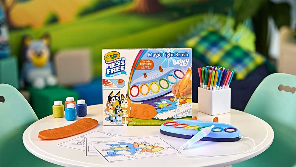 Crayola Color Wonder Magic Light Brush packaging and contents on child's table with kids paint and markers.