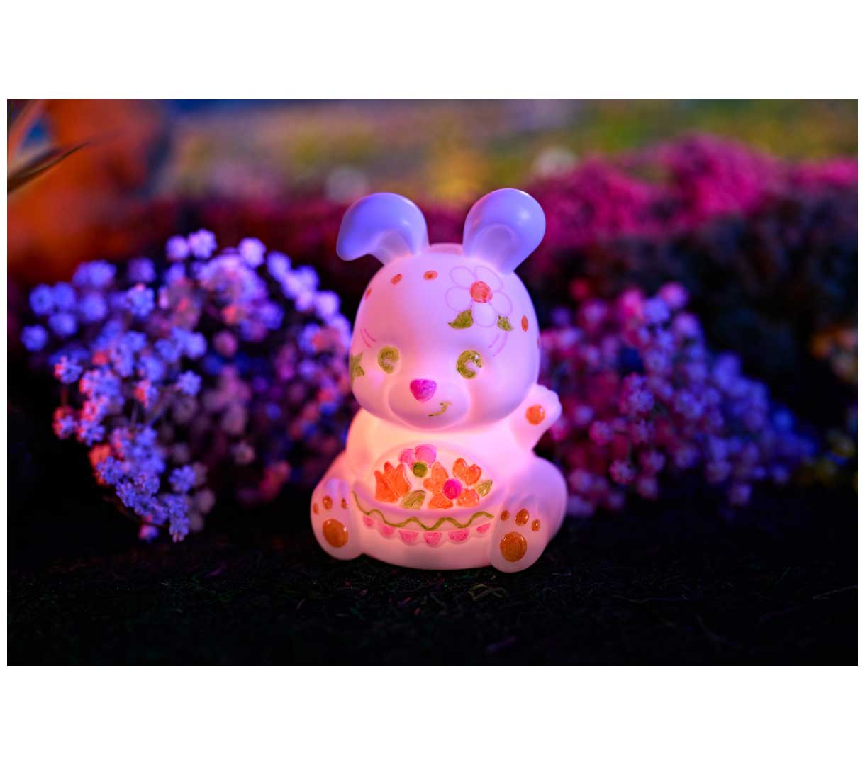 Light-Ups Bunny decorated and glowing pink in front of flowers.