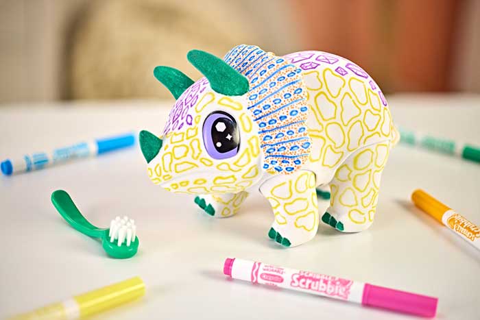 Scribble Scrubbie Jumbo Pet, Rory the Dino. Decorated Rory surrounded by washable markers and one scrub brush.