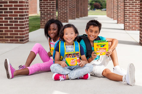 Three diverse children holding Crayola projects
